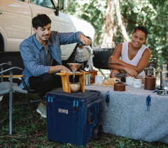 Man and woman sitting in a camping ground making a hot beverage