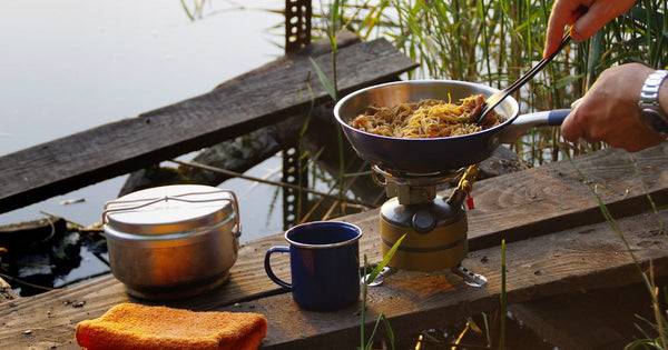person cooking on a camp gas stove