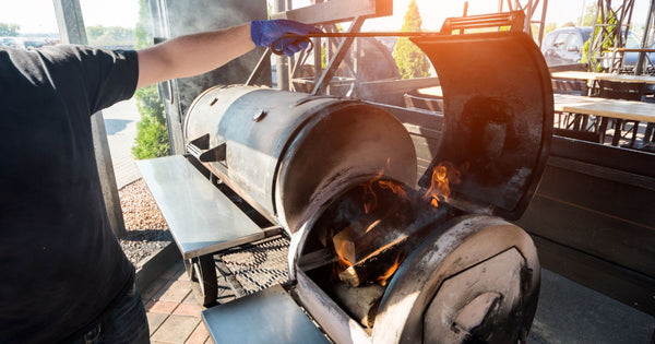 Person heating up a smoker with a fire